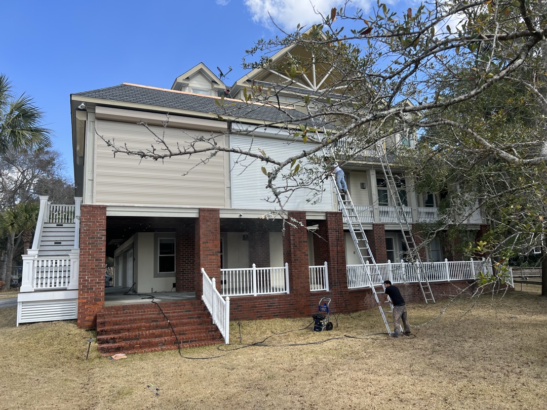 Waterfront home back before painting with crew on ladder